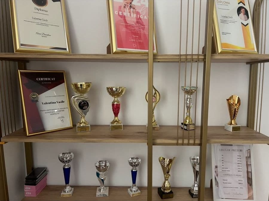 Raftul cu diplomele și cupele Valentinei, cu lista ei de prețuri alături